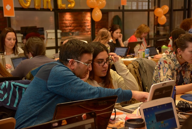 Image of adults looking at laptps in a busy coffeeshop