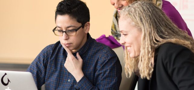 Three women look at a computer screen