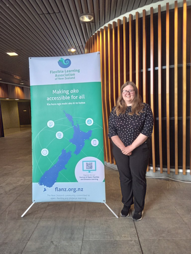 Jennifer Kirby standing in front of a FLANZ banner