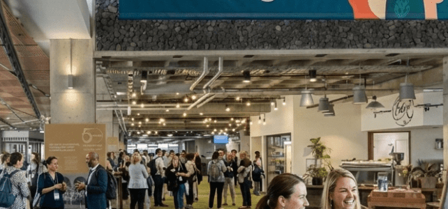 Interior of a conference center with people in it and large banner at the top that reads "FLANZ Conference 2026: He Tāngata"